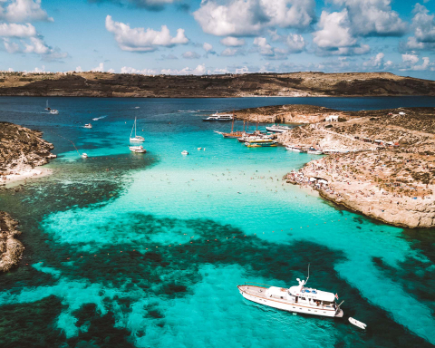 Enseada de águas cristalinas em Malta com veleiros ancorados.